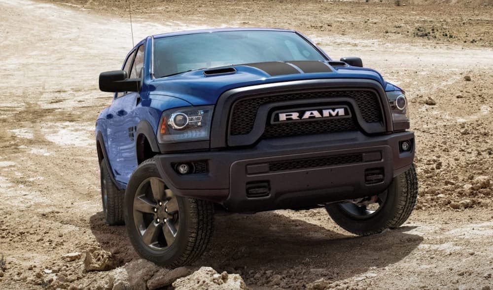 A blue 2019 Ram 1500 is shown from the front off-roading in the mountains. 