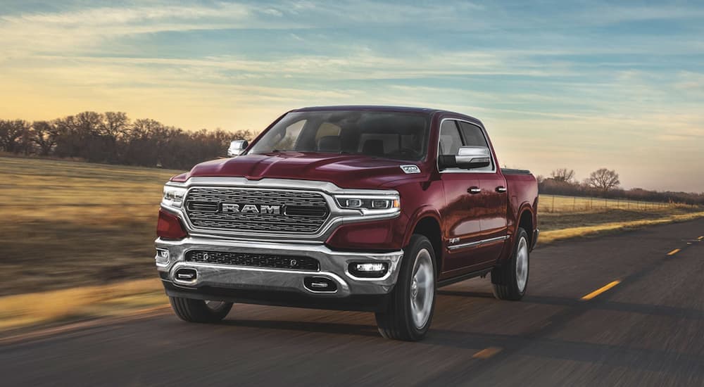 A red 2020 Ram 1500 is shown from the front driving on an open road at sunset.