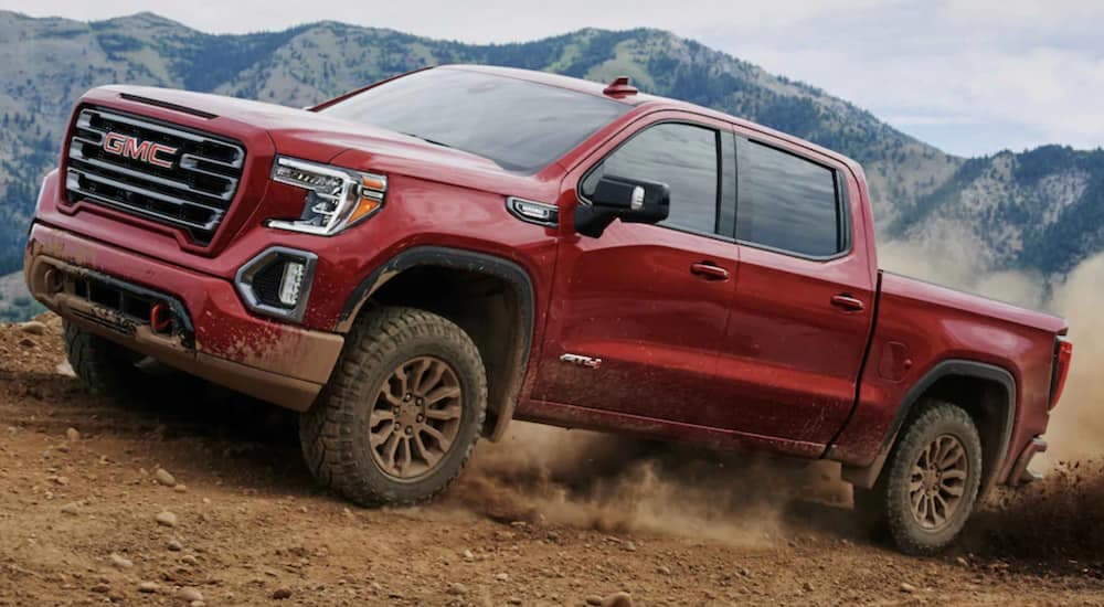 A red 2021 GMC Sierra AT4 is shown off-roading in the mountains.