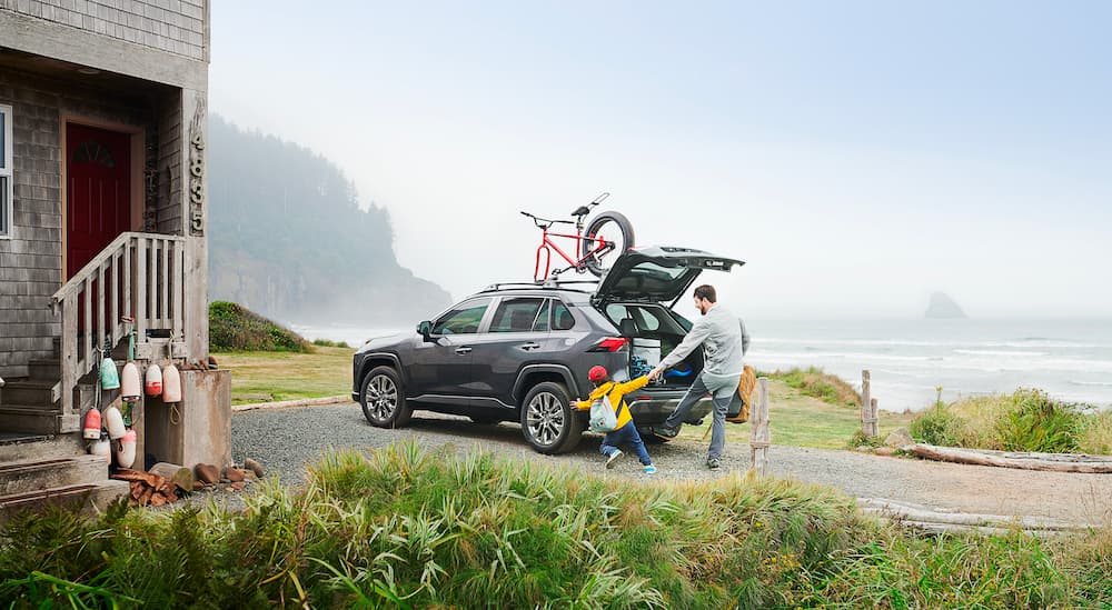 A father and son are shown next to a 2021 Toyota RAV4 Limited near the ocean.