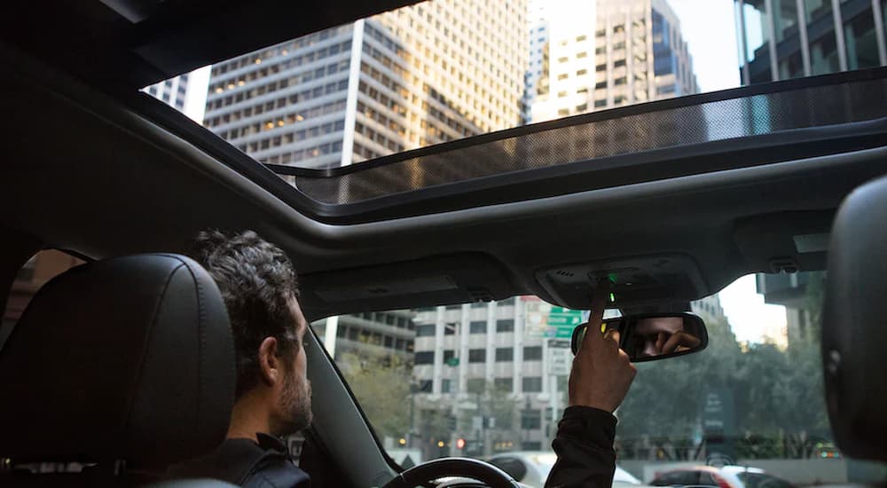 A man is shown opening the sunroof of a 2022 Chevy Malibu.