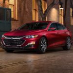 A red 2022 Chevy Malibu is shown parked on a city side street.
