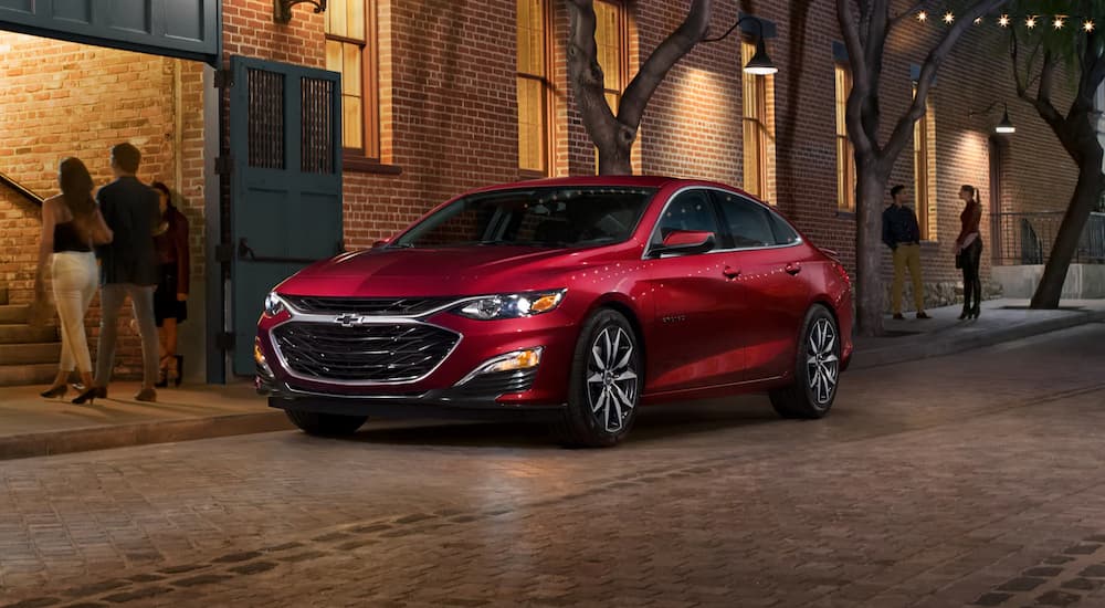 A red 2022 Chevy Malibu is shown parked on a city side street.