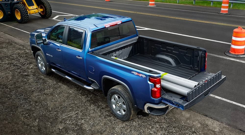 Grey pipes are shown in the bed of a blue 2022 Chevy Silverado 2500HD.