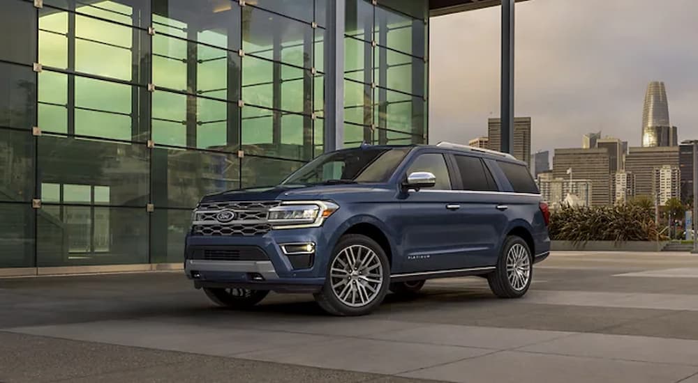 A blue 2022 Ford Expedition is shown parked outside of a glass building.