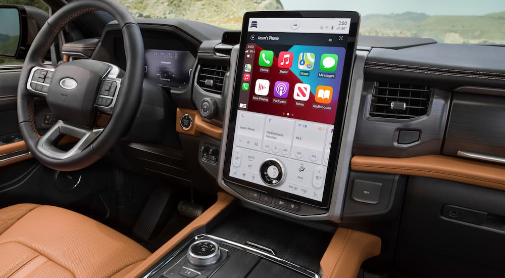 The brown and black interior of a 2022 Ford Expedition Platinum shows the steering wheel and infotainment screen.