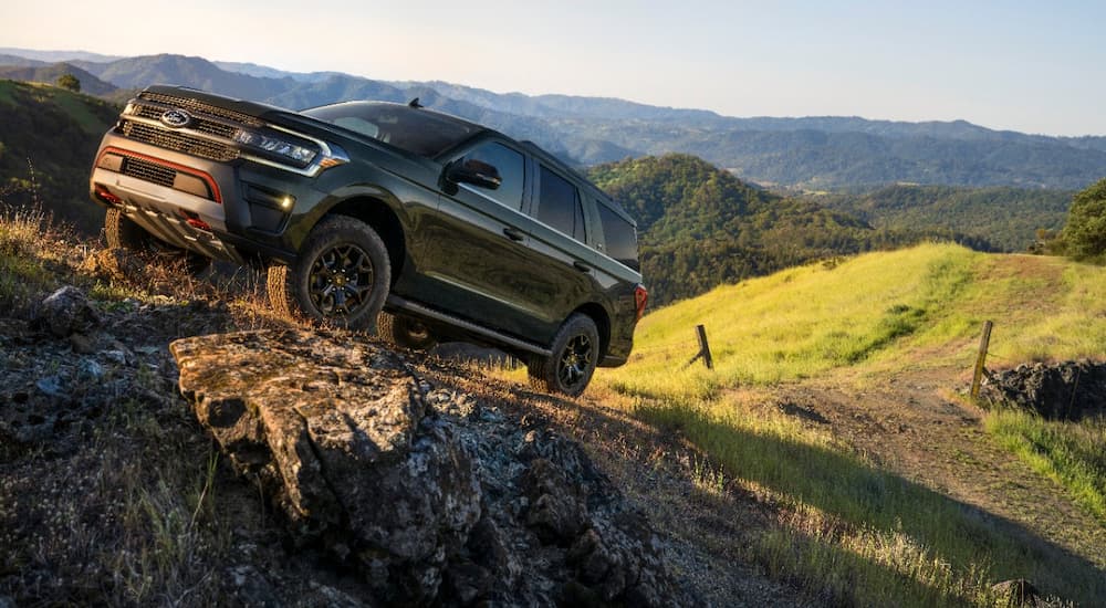 A green 2022 Ford Expedition Timberline is shown driving up a steep mountain road.