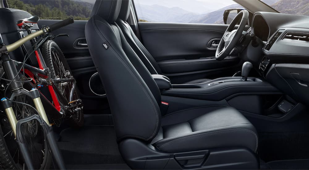 The black leather interior of a 2022 Honda HR-V EX-L shows the front seats and a bicycle.