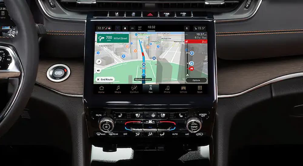 The black and silver interior of a 2022 Jeep Grand Cherokee shows the GPS app on the infotainment screen.