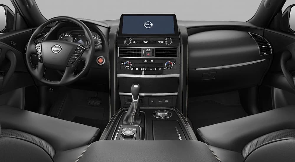 The black interior of a 2022 Nissan Armada Midnight Edition shows the steering wheel and infotainment screen.