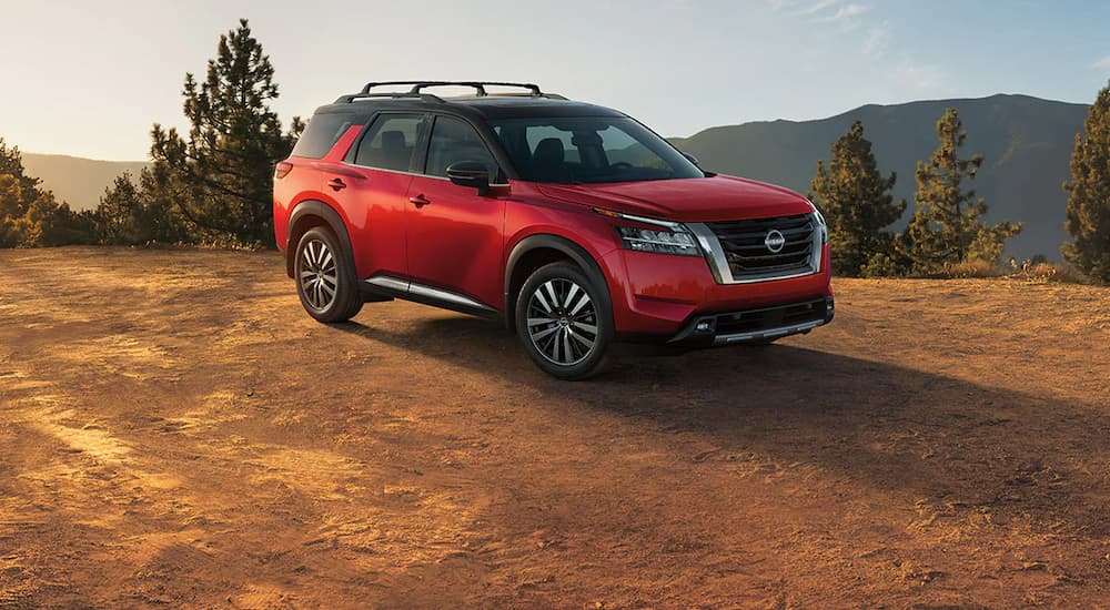 A red 2022 Nissan Pathfinder is shown parked in an open area during a 2022 Nissan Pathfinder vs 2022 Subaru Ascent comparison.