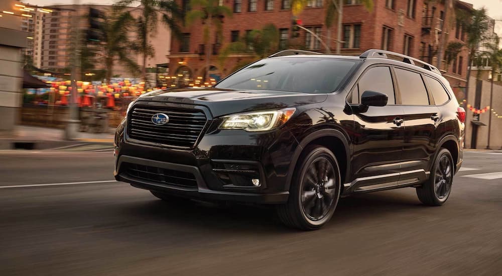 A black 2022 Subaru Ascent is shown driving on a city street.