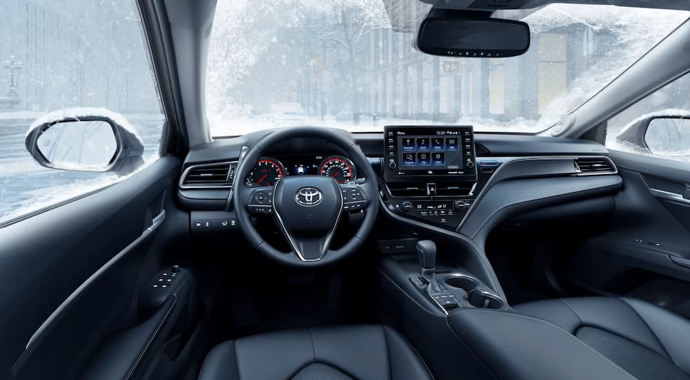 The black leather interior of a 2022 Toyota Camry is shown during a snowstorm.