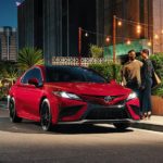 A red 2022 Toyota Camry is shown parked outside of a restaurant.