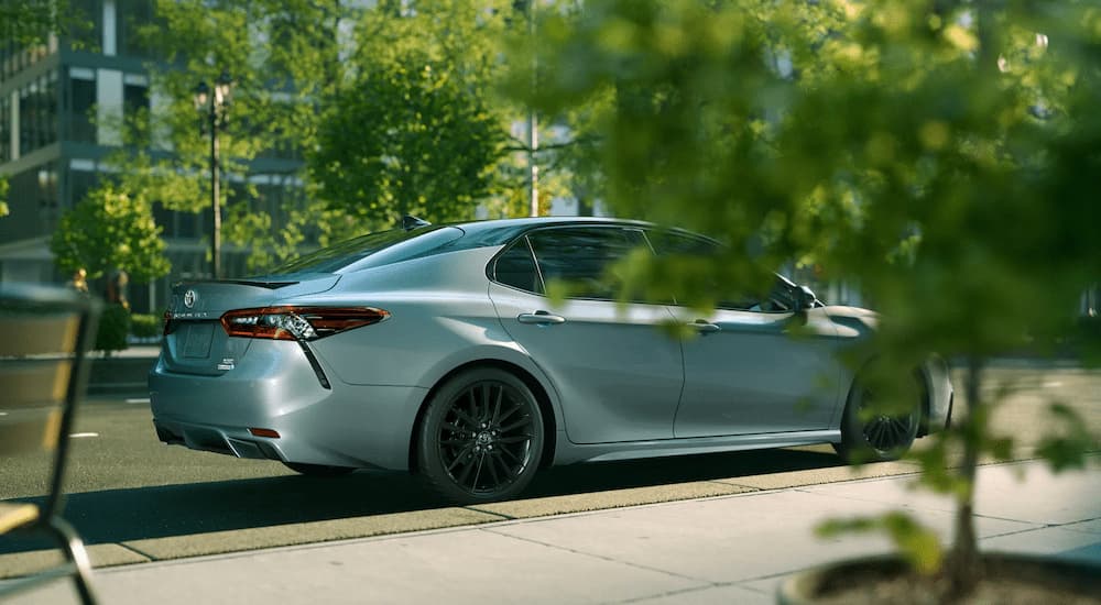 A silver 2022 Toyota Camry is shown from a side angle parked on a city street.