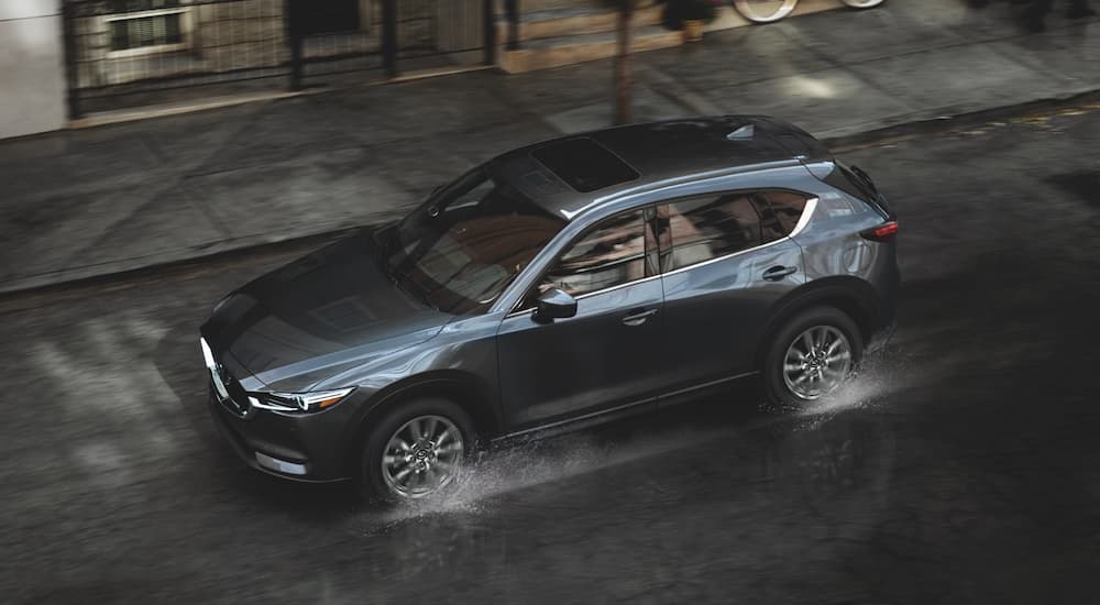 A grey 2021 Mazda CX-5 is shown from a high angle driving on a city street.