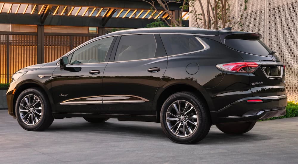 A black 2022 Buick Enclave Avenir is shown from the side near a Buick dealership.