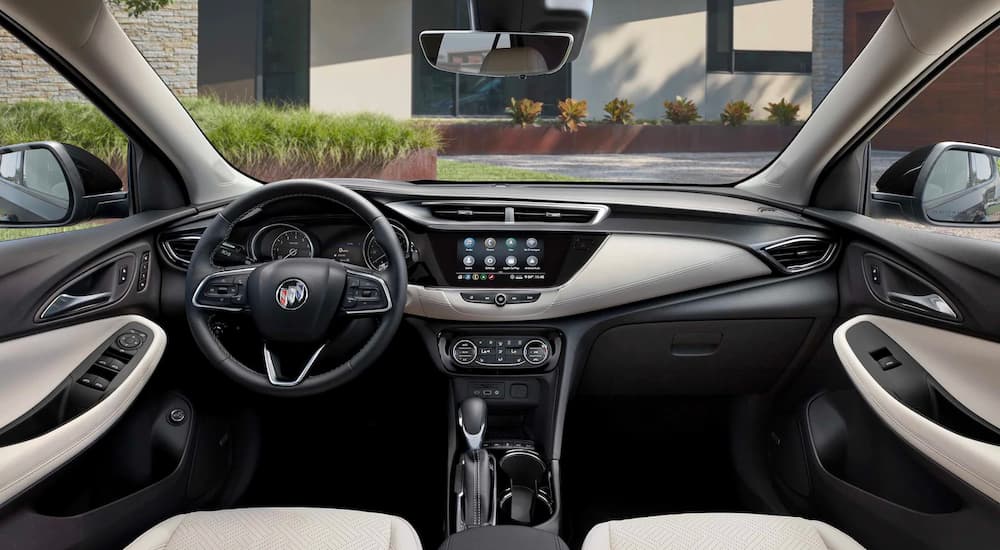 The white and black interior of a 2022 Buick Encore GX shows the steering wheel and infotainment screen.