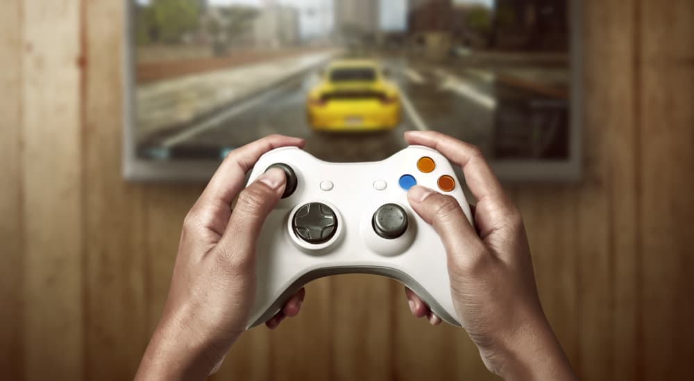 A person is shown holding a video game controller playing a racing game.