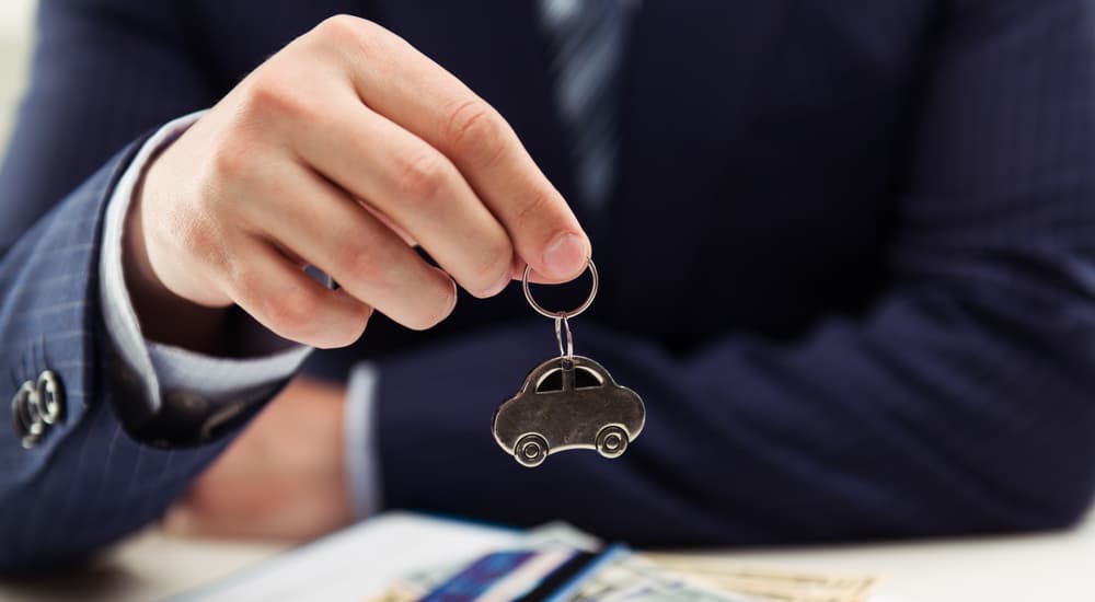 A man is shown holding a car-shaped keychain during a Chevy end of lease meeting.