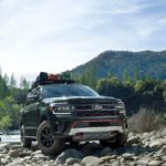 A green 2022 Ford Expedition Timberline is shown parked on rocks near a river.