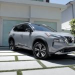 A silver 2021 Nissan Rogue is shown parked outside of a modern home.