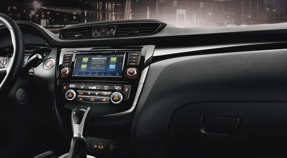 The black and silver accented interior of a 2021 Nissan Rogue Sport shows the infotainment screen.