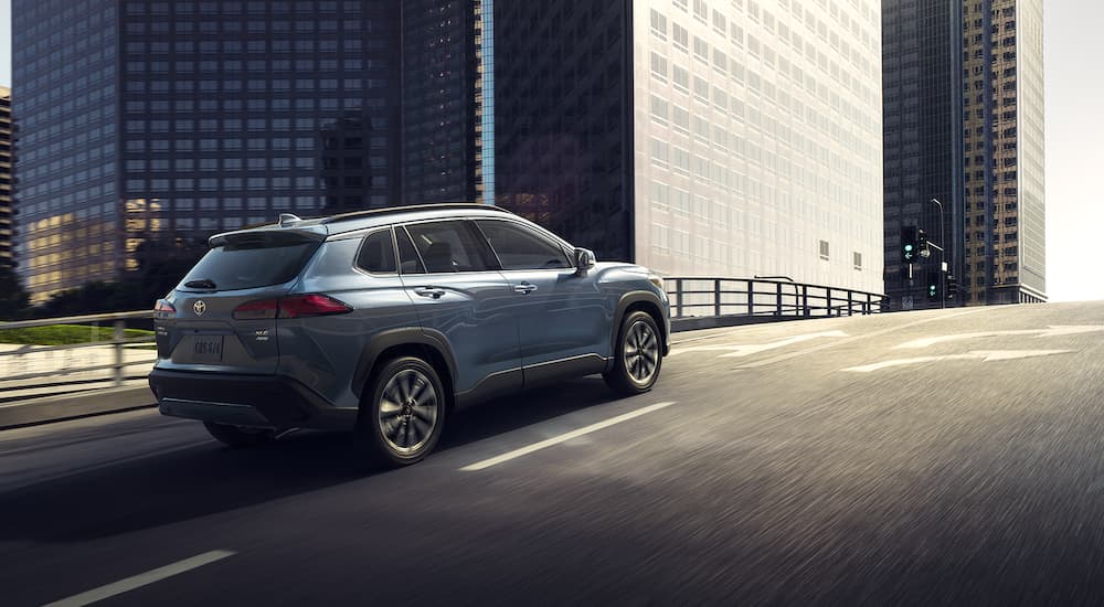 A blue 2022 Toyota Corolla Cross XLE is shown driving through a city after visiting a Reading Toyota dealership.