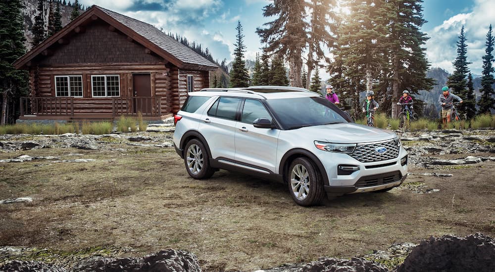 A white 2021 Ford Explorer is shown parked outside of a remote cabin.
