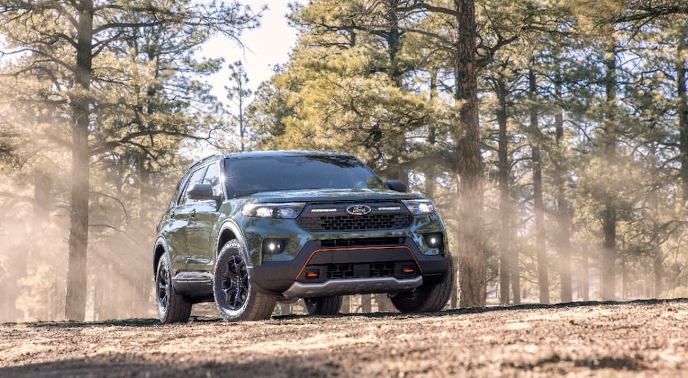A green 2021 Ford Explorer Timberline is shown driving on a trail through the woods.