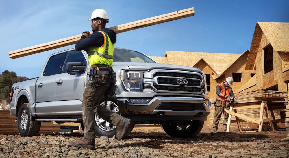 A man is shown carrying boards at a construction site near a silver 2021 Ford F-150 XLT.