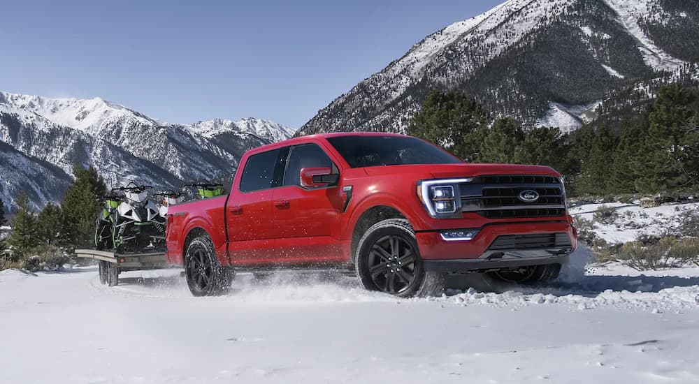 A red 2021 Ford F-150 is shown driving through an open snow-covered area.