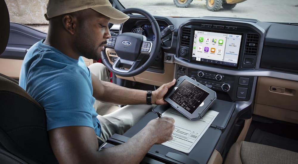 A man is shown looking at paperwork inside of a 2021 Ford F-150.