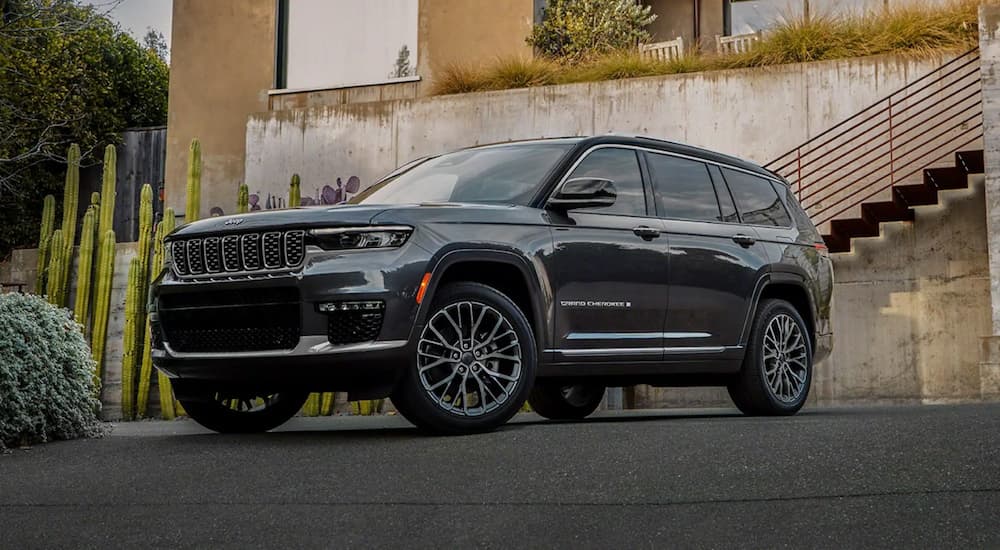 A grey 2021 Jeep Grand Cherokee L is shown parked outside of a modern home during a 2021 Jeep Grand Cherokee L vs 2021 Toyota Highlander comparison.