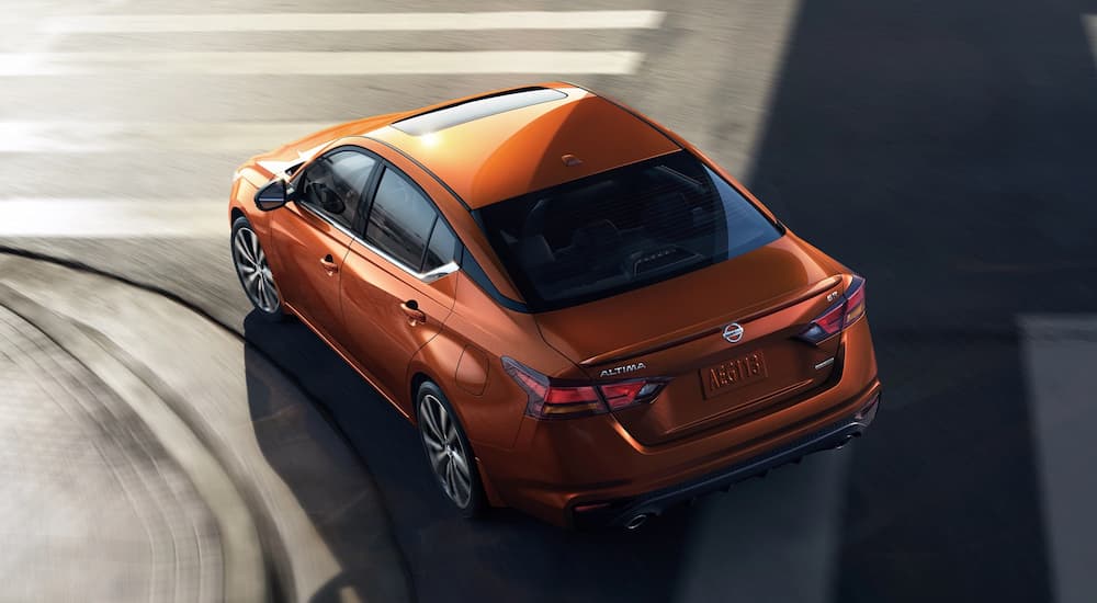 The rear of a orange 2021 Nissan Altima is shown from a high angle.