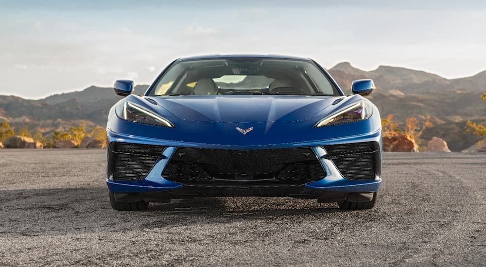 A blue 2022 Chevy Corvette is shown from the front parked in a desert area.