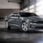 A grey 2022 Chevy Camaro is shown driving in a parking garage.