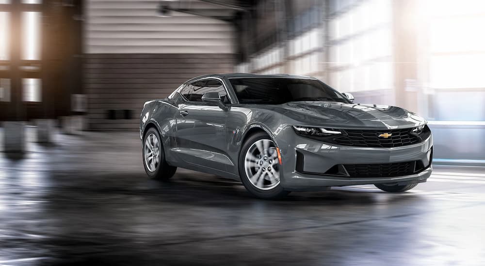 A grey 2022 Chevy Camaro is shown driving in a parking garage.