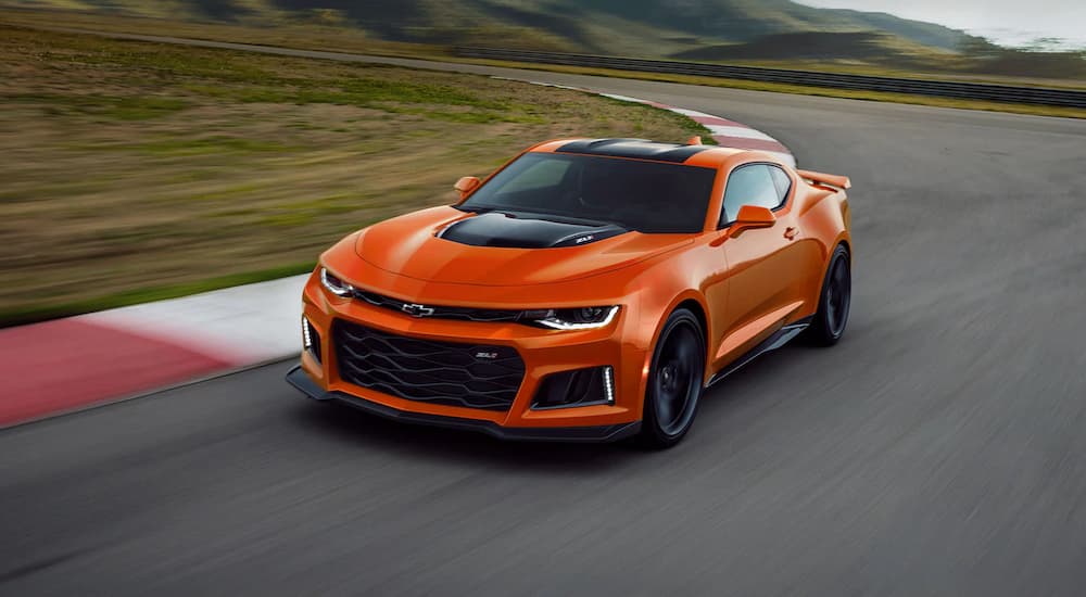 An orange 2022 Chevy Camaro ZL1 is shown driving on a track.