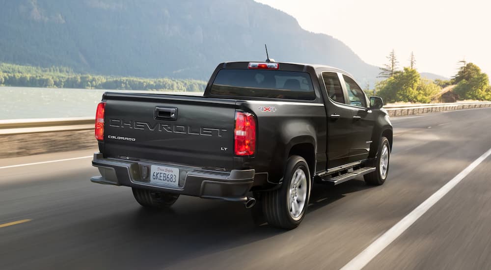 A black 2022 Chevy Colorado LT is shown from the rear driving near a body of water.