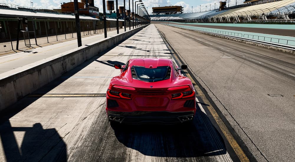 A red 2022 Chevy Corvette is shown from the rear parked on a racetrack.