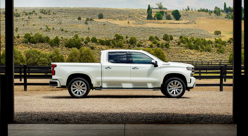 A white 2022 Chevy Silverado 1500 High Country is shown from the side parked at a farm.