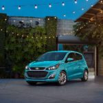 A blue 2022 Chevy Spark is shown parked in a courtyard.