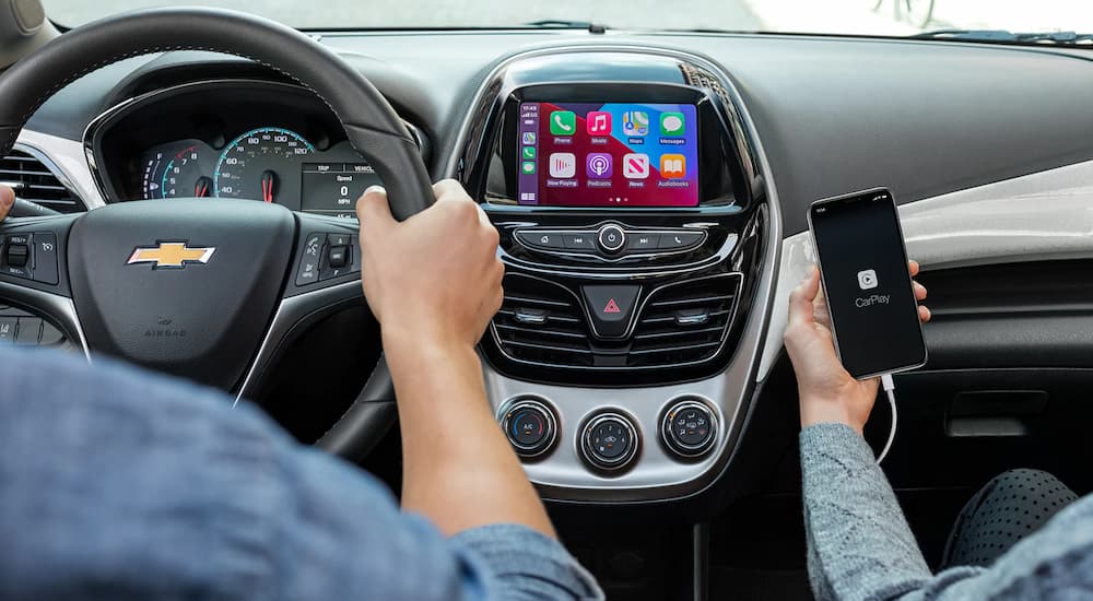 The interior of a 2022 Chevy Spark shows a couple driving and using Apple CarPlay.