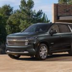 A green 2022 Chevy Tahoe High Country is shown parked outside of a modern home.