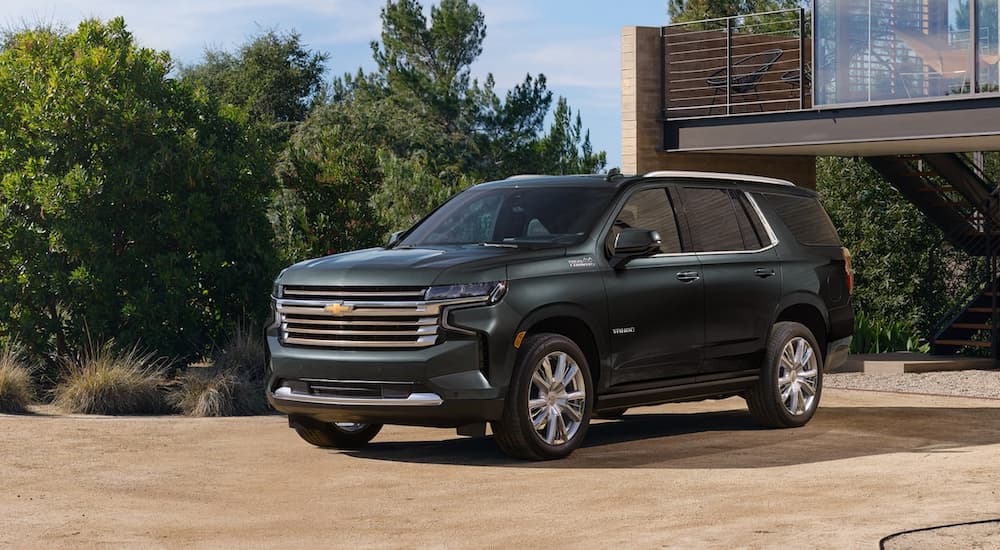 A green 2022 Chevy Tahoe High Country is shown parked outside of a modern home.