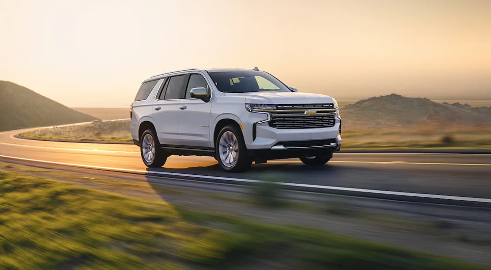 A white 2022 Chevy Tahoe Premier is shown driving on an empty foggy road.