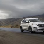 A silver 2022 Ford Edge is shown driving on an empty foggy road.