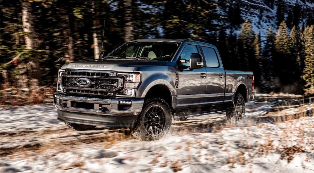 A black 2022 Ford F-250 Super Duty Black Appearance Package is shown driving through a snowy field. 