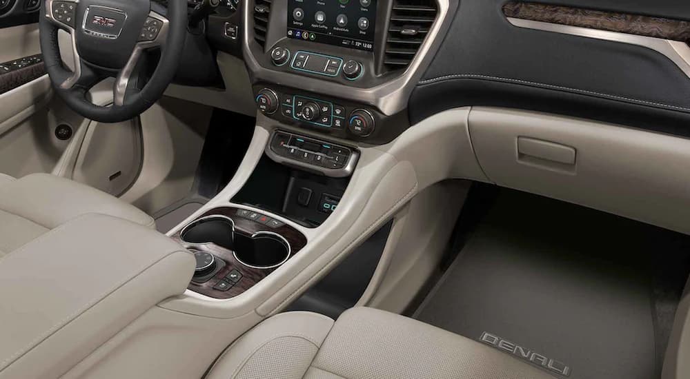 The black and tan interior of a 2022 GMC Acadia shows the center console.